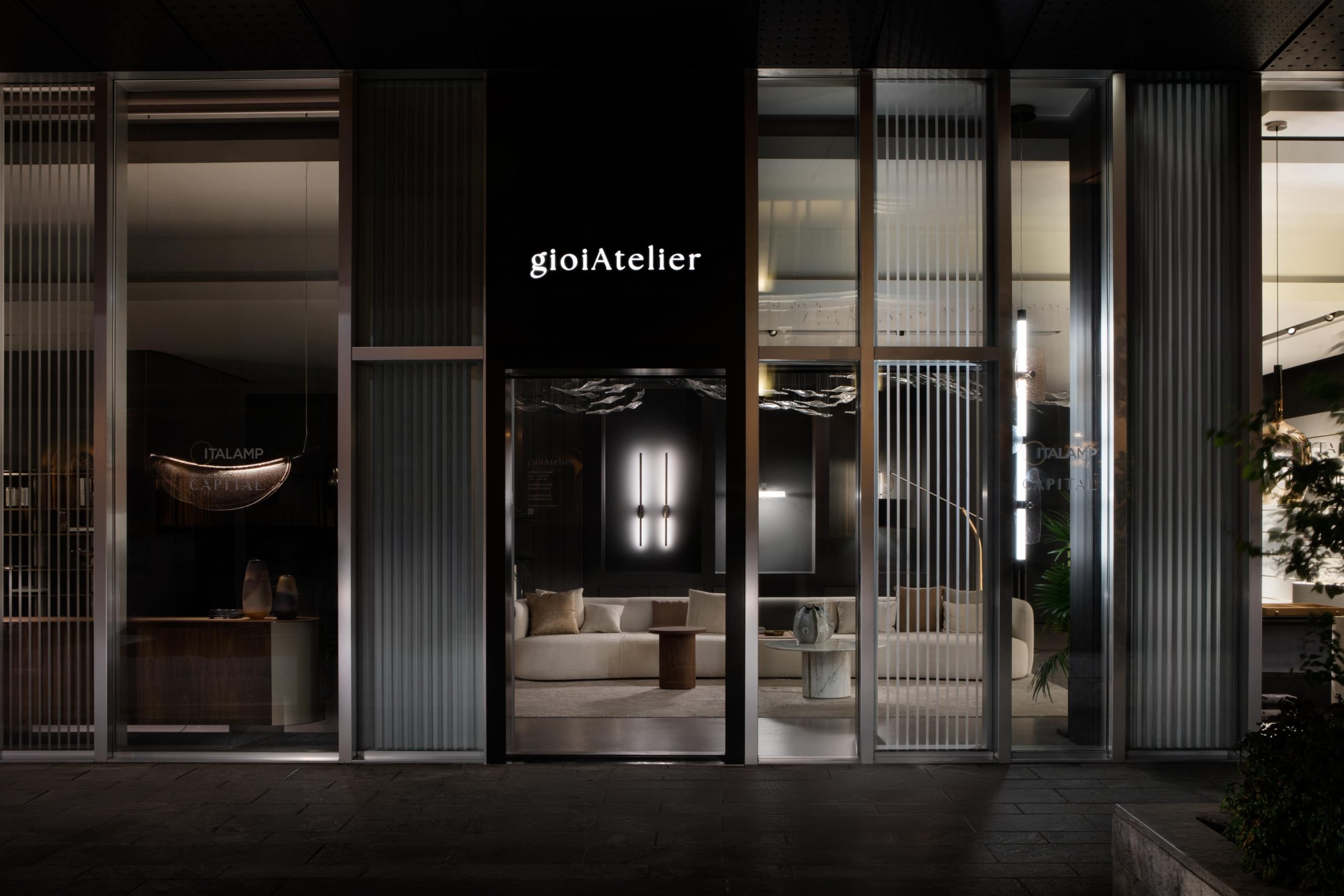 L'esterno dello showroom gioiAtelier Milano alle luci della notte, in cui spicca l'insegna luminosa.