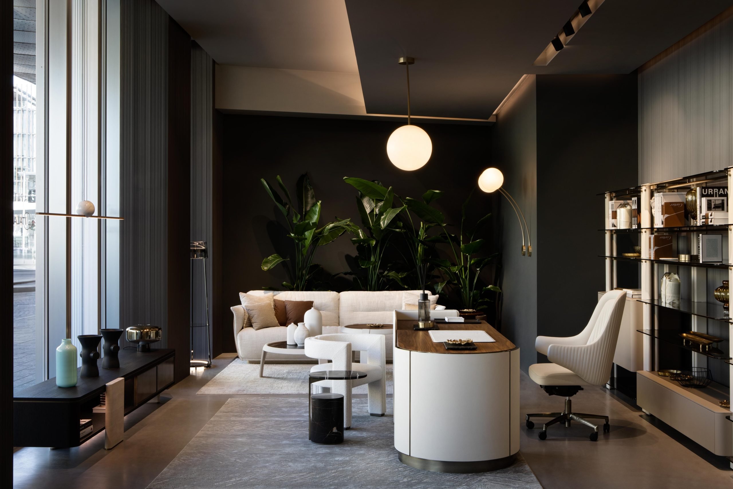 Un angolo elegante dello showroom arredato con una scrivania, una sedia da lavoro, un divano, tutti complementi candidi.